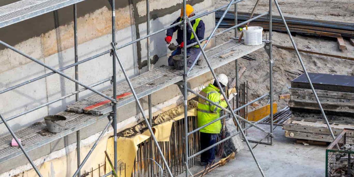 Homens trabalhando em construção civil utilizando equipamentos de proteção individual (EPI)