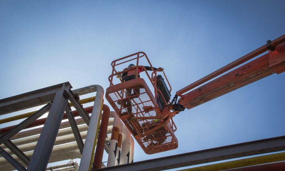 Homens trabalhando em cima de plataforma elevatória elétrica